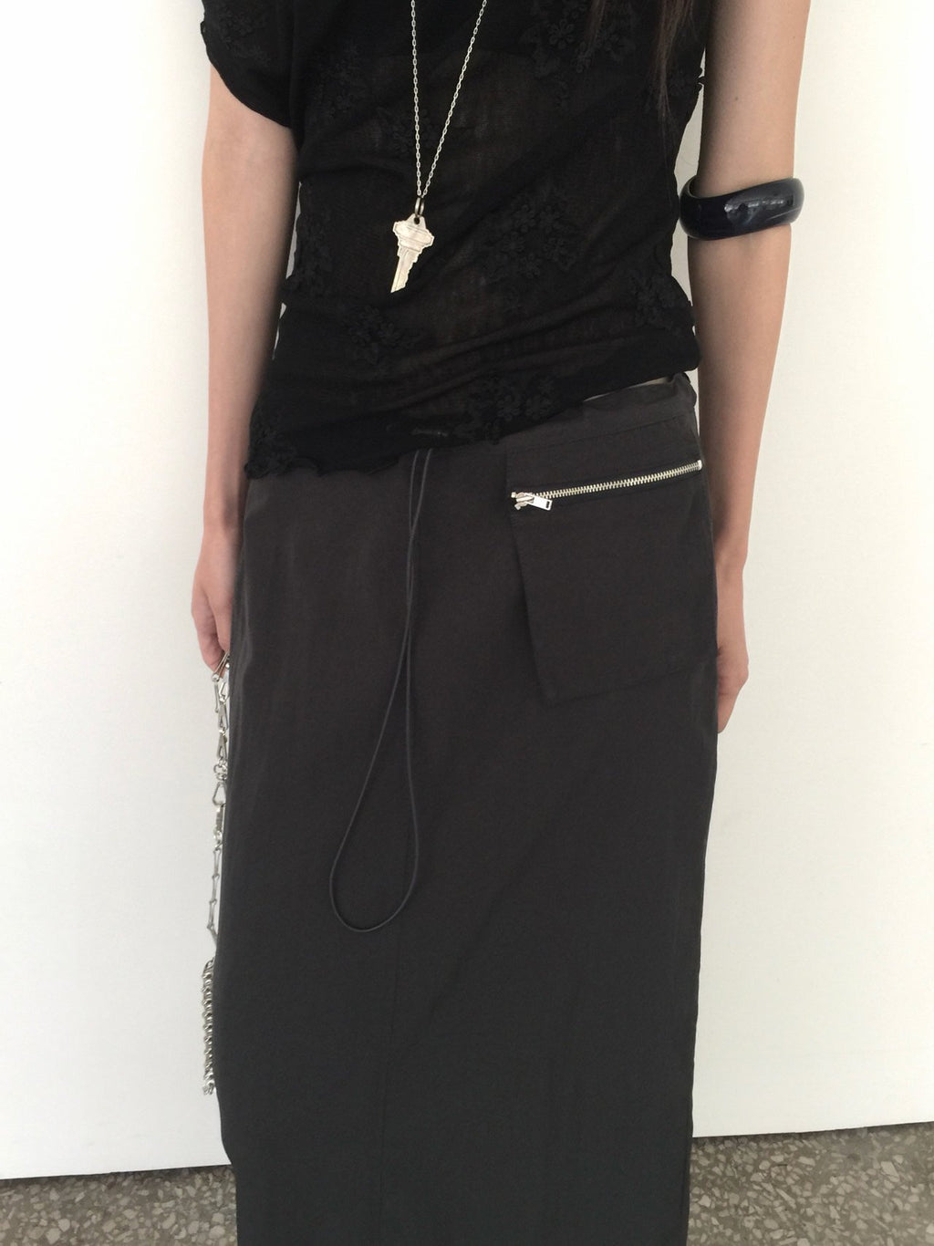 Nweol low rise zip pocket maxi skirt in Black, styled on model side view with chain bag