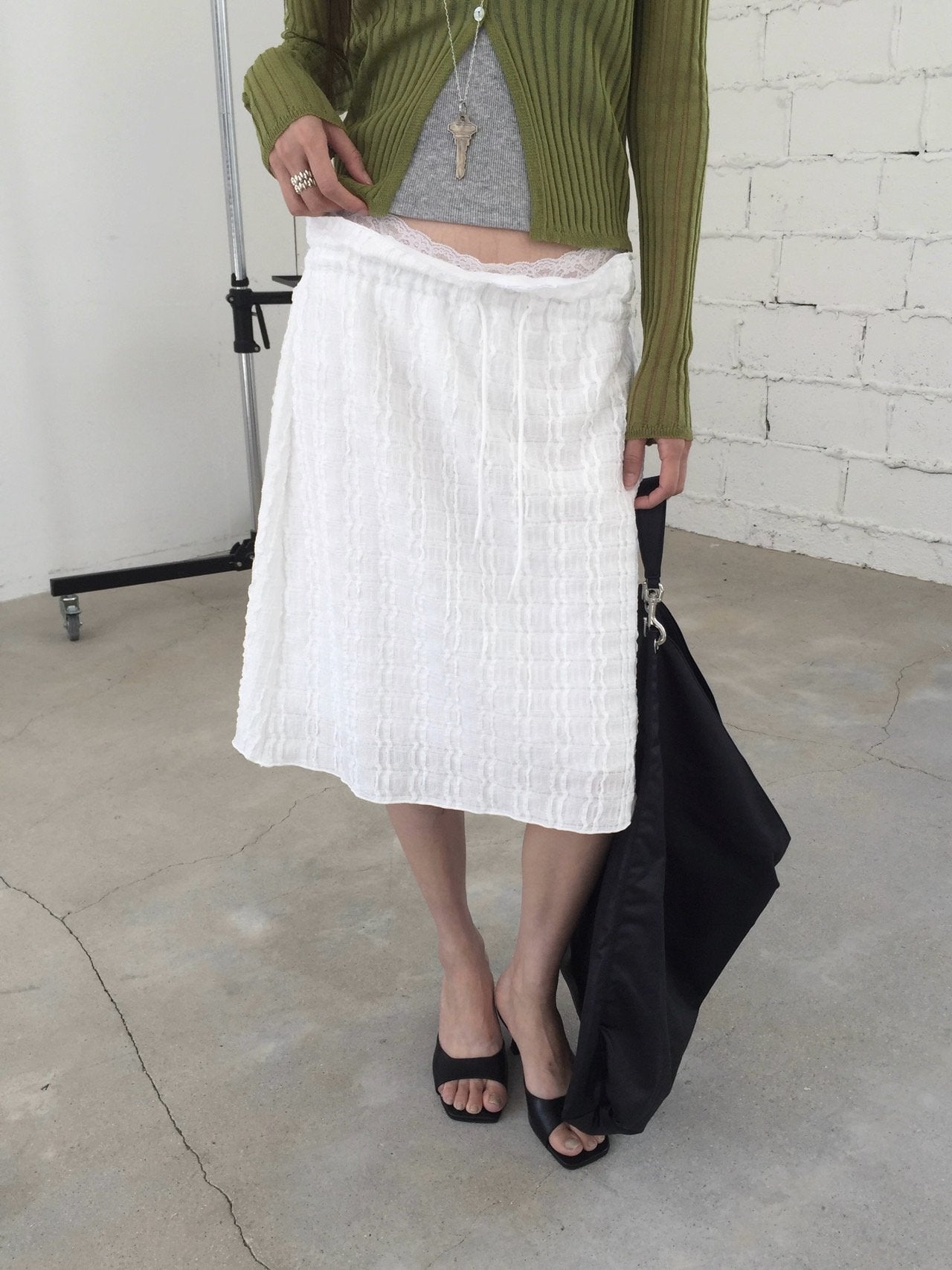 Nweol bubble texture midi skirt in Black, styled on model seated front view with white tank top and light green cardigan