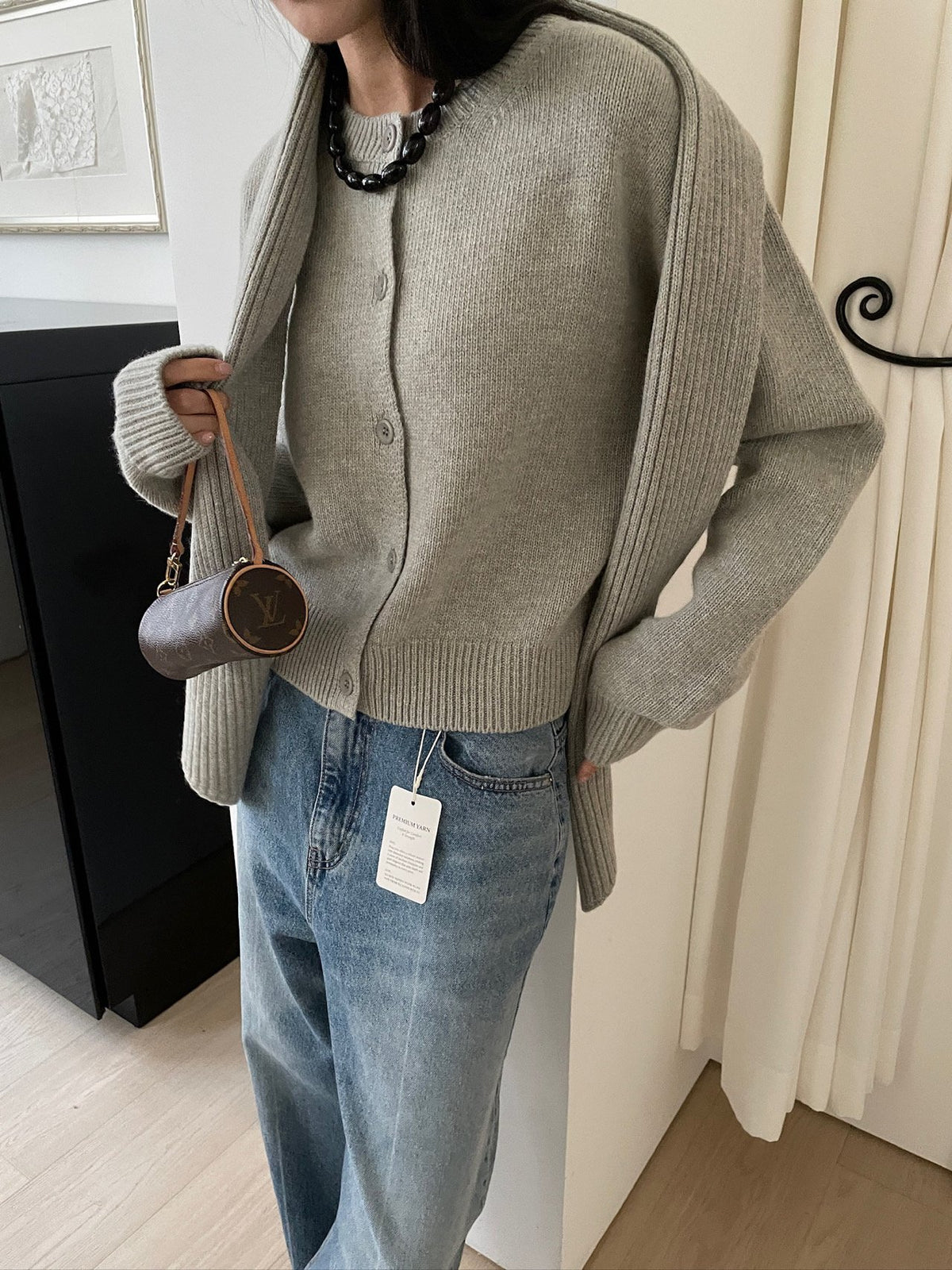 Front view of khaki cardigan with scarf draped over shoulders