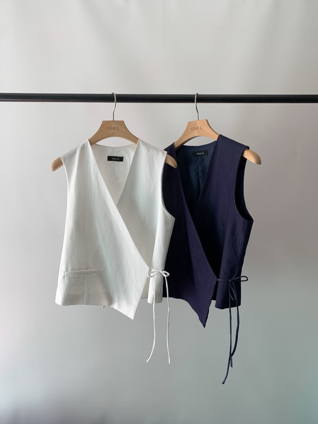 Vivel cross wrap vest in White and Navy, two colorways product flat lay on rack hanger against grey background