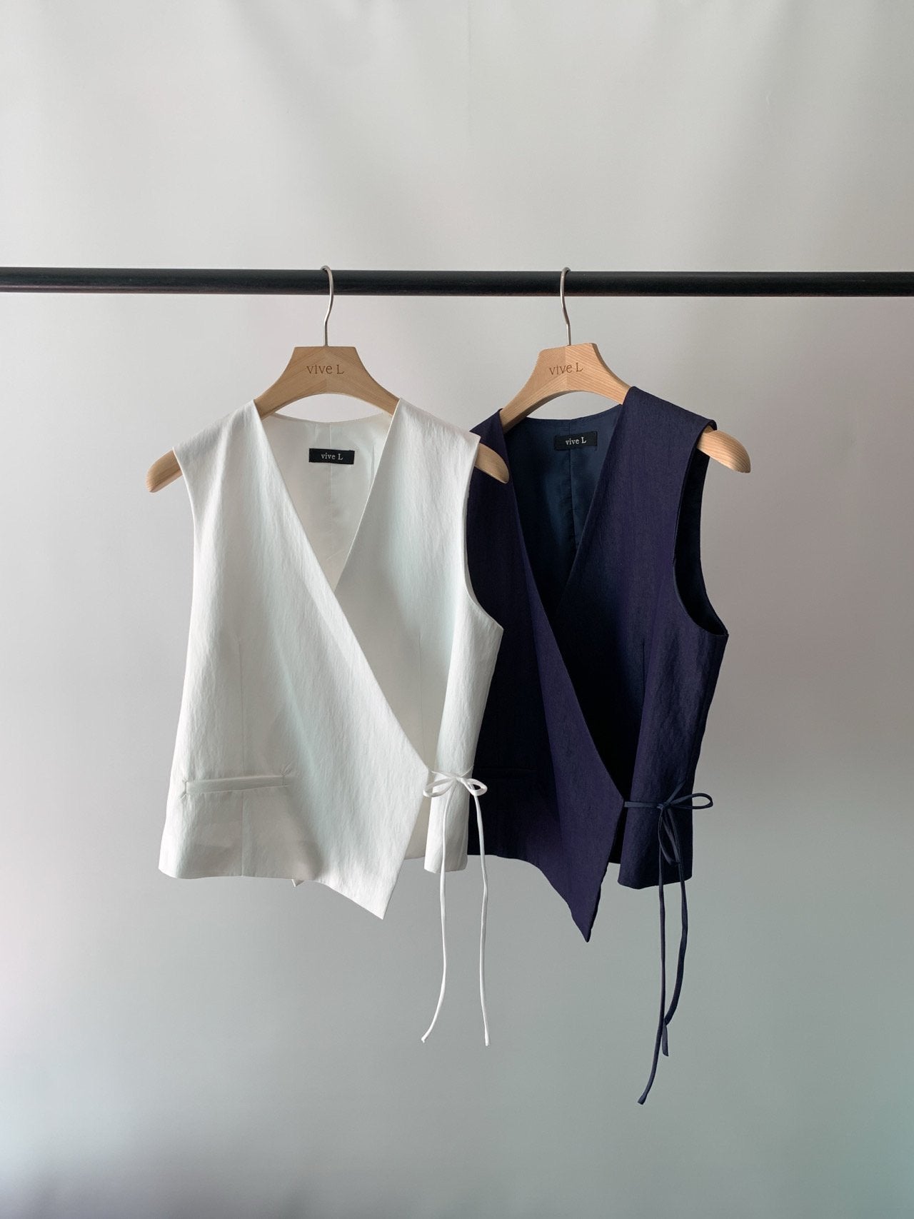 Vivel cross wrap vest in White and Navy, two colorways product flat lay on rack hanger against grey background